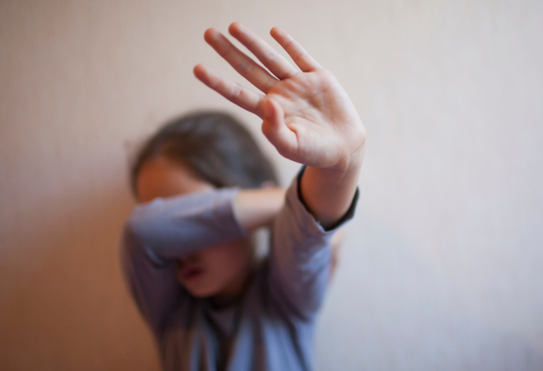 Child covering face with hand up